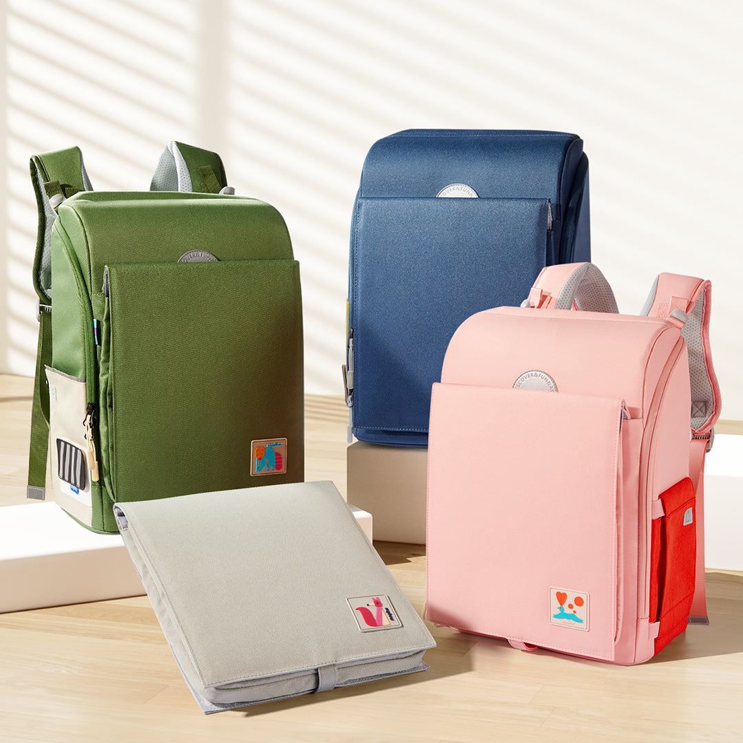 Ergonomic 3D Waist-Relief Backpacks in green, blue, and pink shades with waterproof material for children aged 6 and up displayed on a wooden surface.